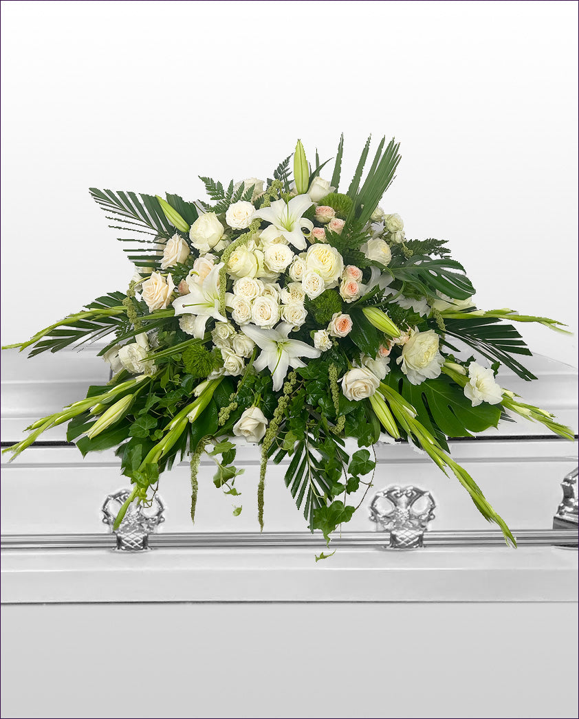 Floral arrangement on a casket with white flowers and green leaves.