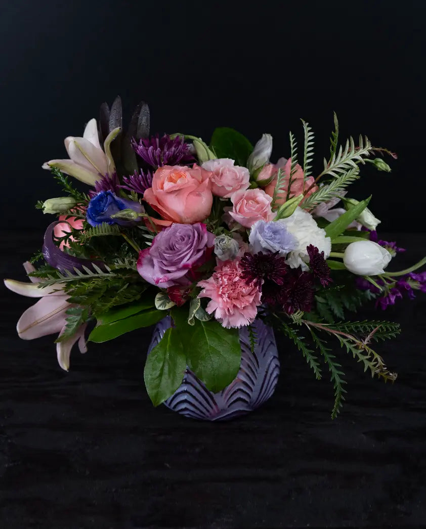 Colorful floral arrangement in a decorative vase on a black background