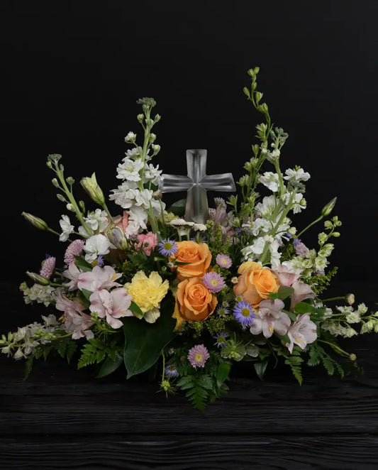 Floral arrangement with a crystal cross on a dark background by bloombudz in Paragould, AR