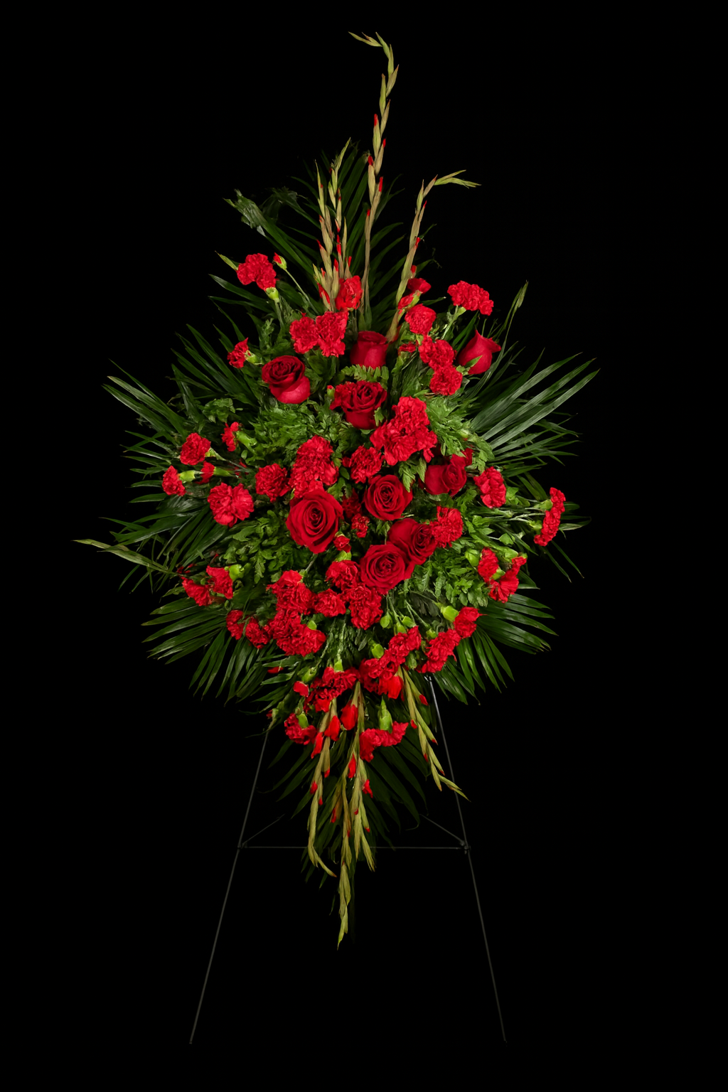 standing spray of red roses with greenery on a black background
