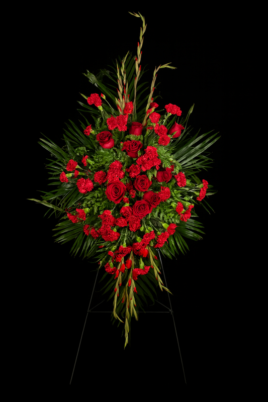standing spray of red roses with greenery on a black background