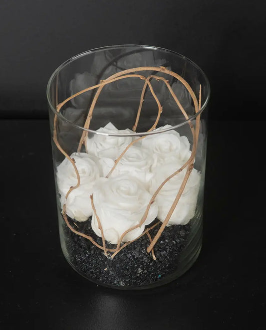 Glass vase with white flowers and branches on a black background