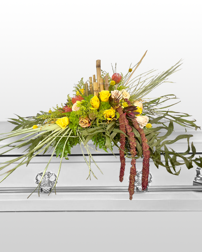 Floral arrangement on a casket with greenery, yellow flowers, and red berries.