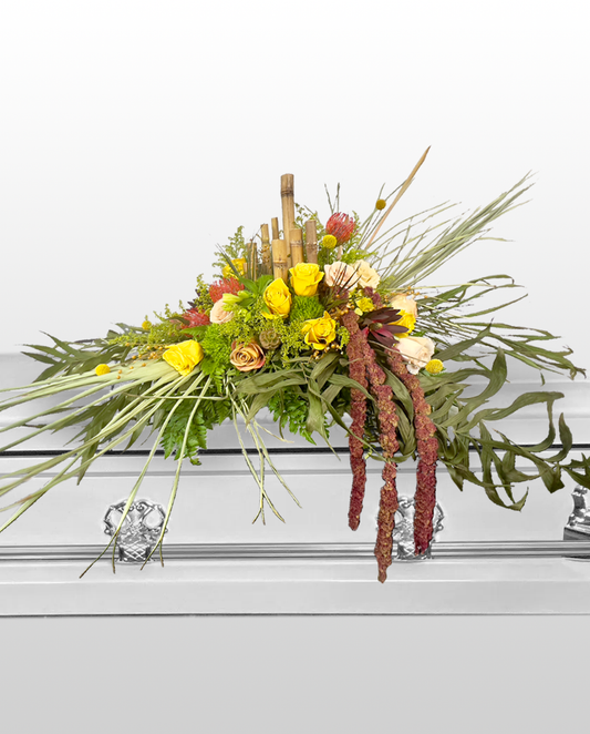 Floral arrangement on a casket with greenery, yellow flowers, and red berries.