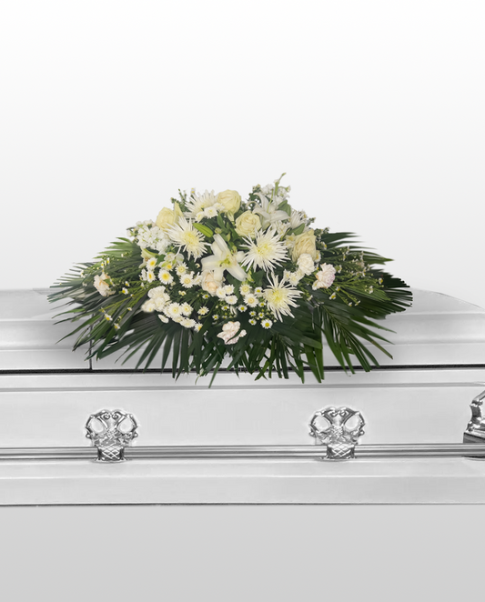 white casket spray arrangement on a white casket with a white background