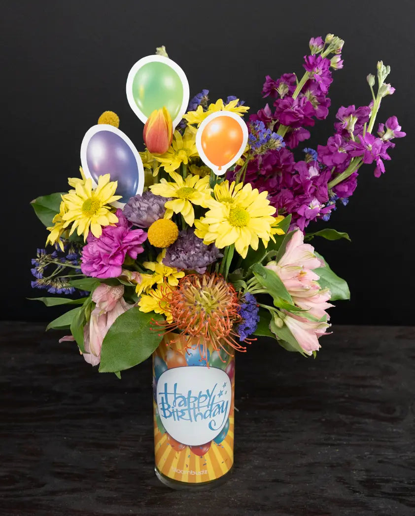 Colorful bouquet with balloons and 'Happy Birthday' vase on a dark background