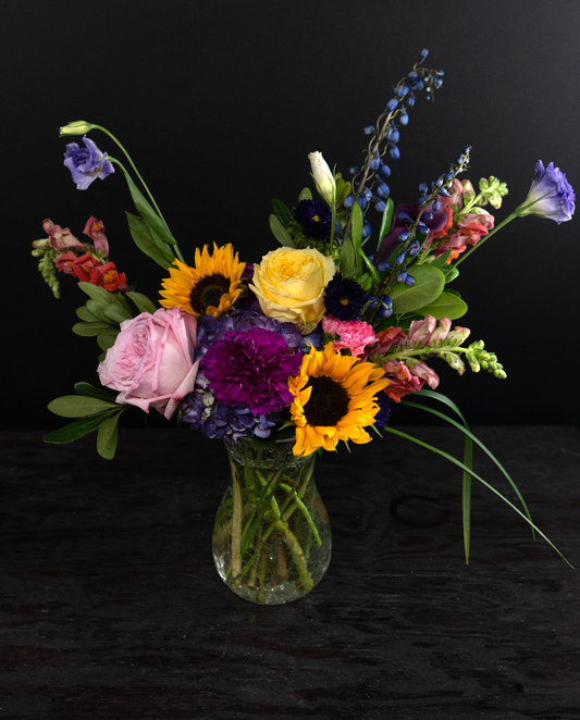 Colorful flower bouquet in a clear vase on a black background