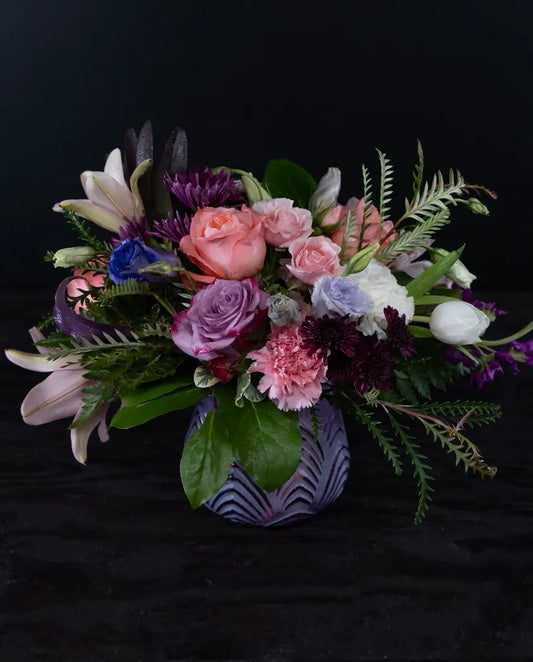 Colorful floral arrangement in a decorative vase on a black background