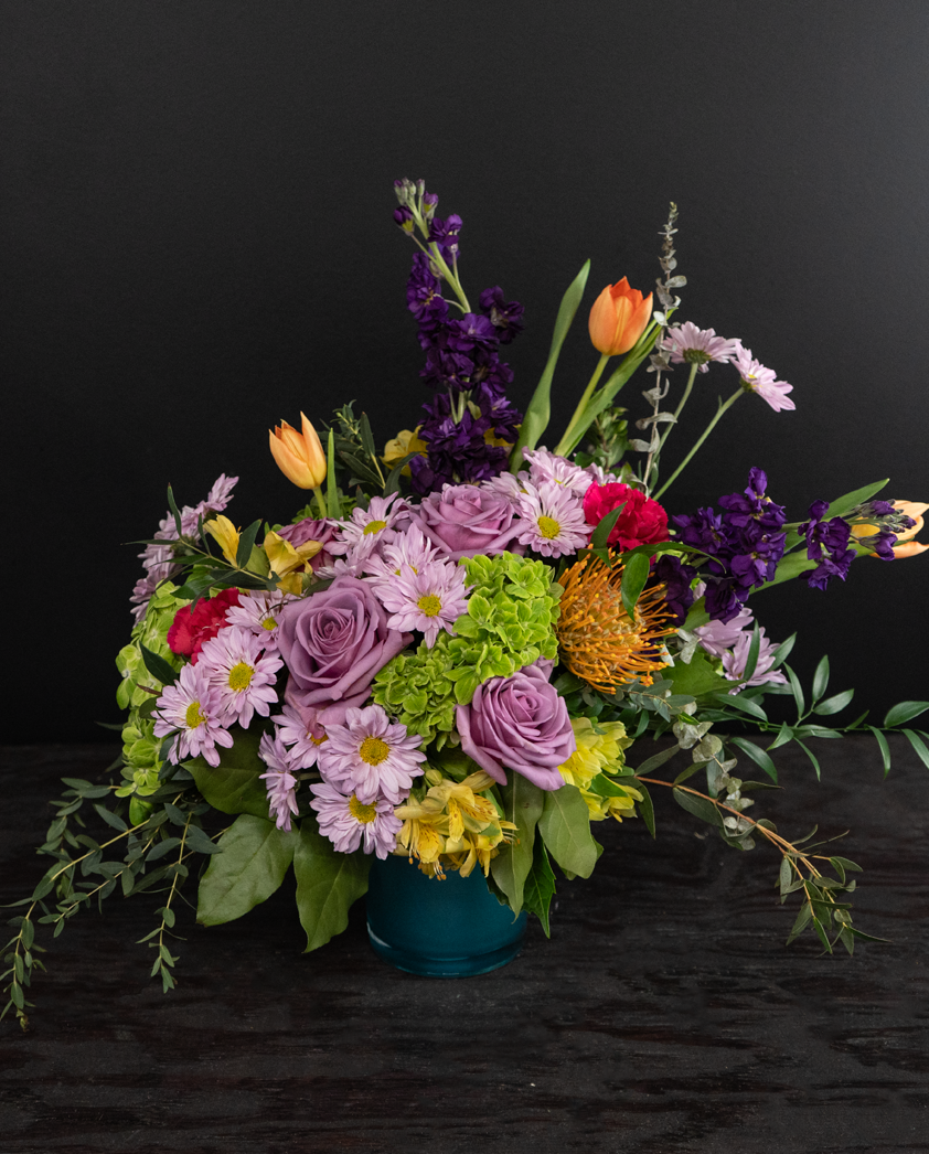 Colorful flower arrangement in a blue container on a black background