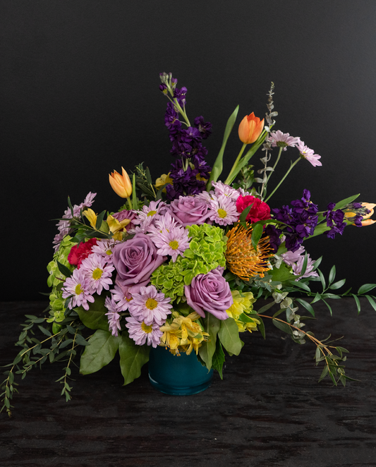 Colorful flower arrangement in a blue container on a black background