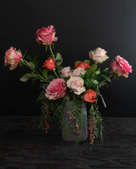 Bouquet of pink and white flowers in a clear vase on a black background