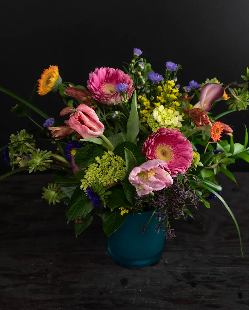 Colorful flower arrangement in a blue vase on a black background