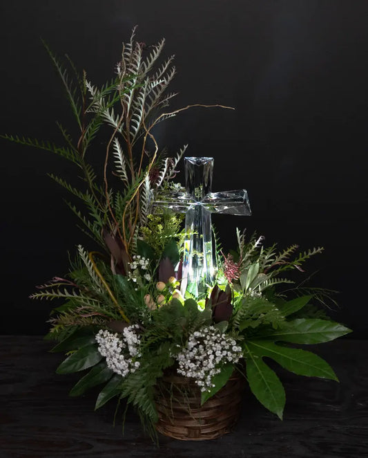 Decorative arrangement with a crystal cross and greenery on a dark background