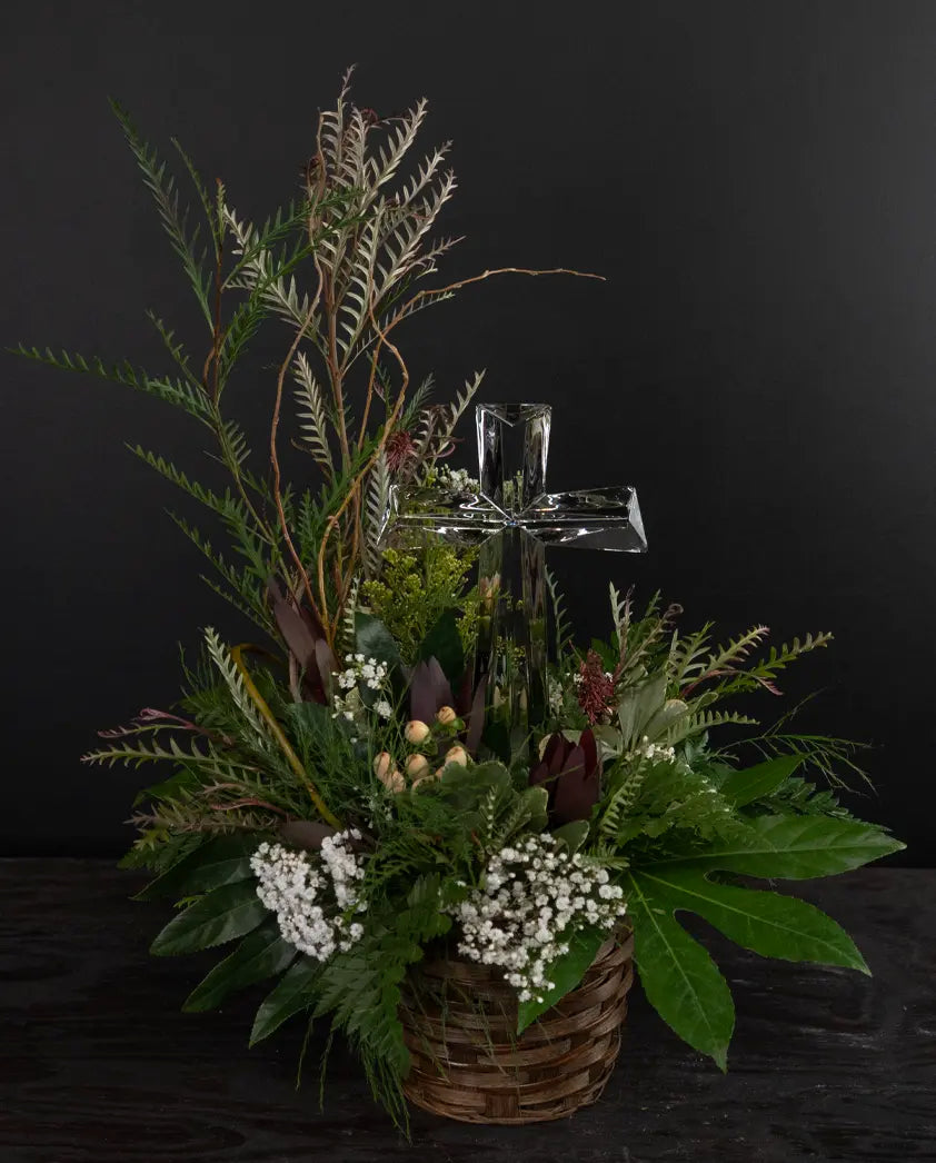 Decorative floral arrangement with a basket and candle on a dark background