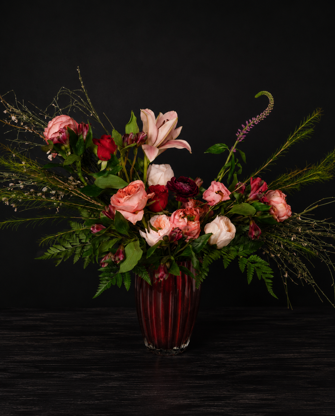 Floral arrangement in a red vase on a dark background