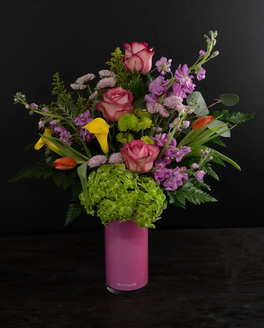 Colorful flower arrangement in a pink vase on a black background