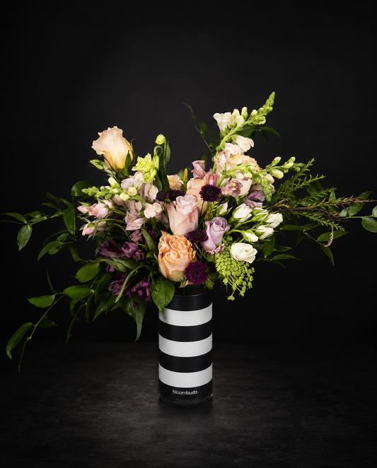 Bouquet of flowers in a black and white striped vase on a dark background