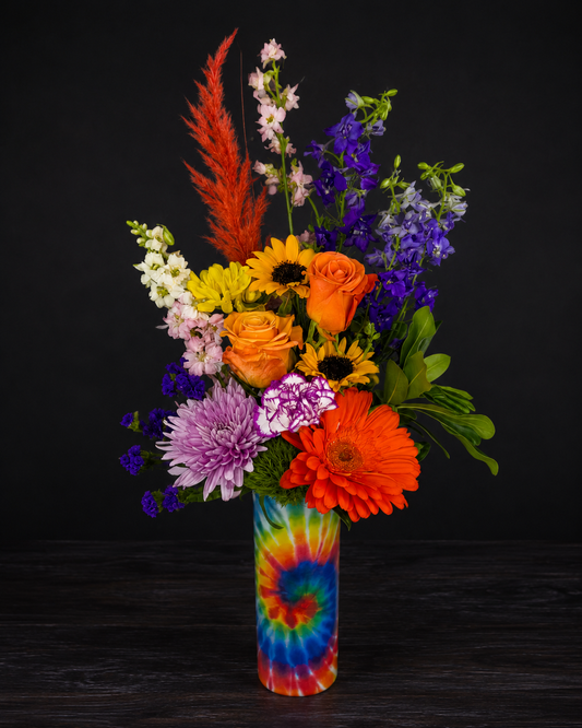 Colorful bouquet of flowers in a tie-dye vase on a dark background